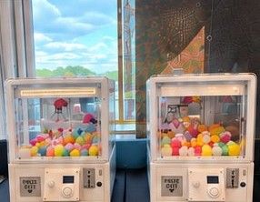 Two white claw machines filled with colorful prize balls at an event