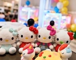 Plush character prizes lined up next to a claw machine